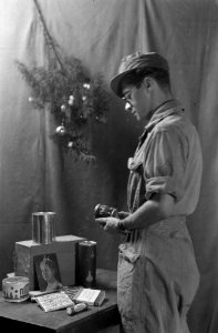 Een soldaat bekijkt de inhoud van een kerstpakket. Geposeerde foto, Bestanddeelnr 8724