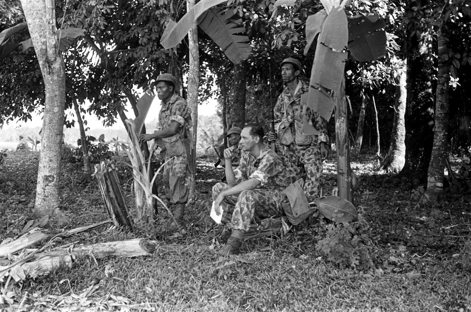 Een sectie KNIL-militairen in camouflage-uniform zitten in een bos, Bestanddeelnr 6449