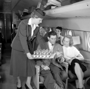 Een stewardess deelt flesjes drank uit, Bestanddeelnr 252-2070