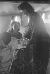Een stewardess in militair uniform brengt iets te drinken rond, onder de passagi, Bestanddeelnr 161-5-1