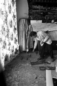Een Turkse man ruimt de rommel op in zijn vernielde woning, na rellen in Afrikaa, Bestanddeelnr 925-8093
