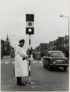Een verkeersagent met een verplaatsbaar verkeersbord op de viersprong Zaanenlaan - Rijksstraatweg - Zaanenstraat. NL-HlmNHA 54004160