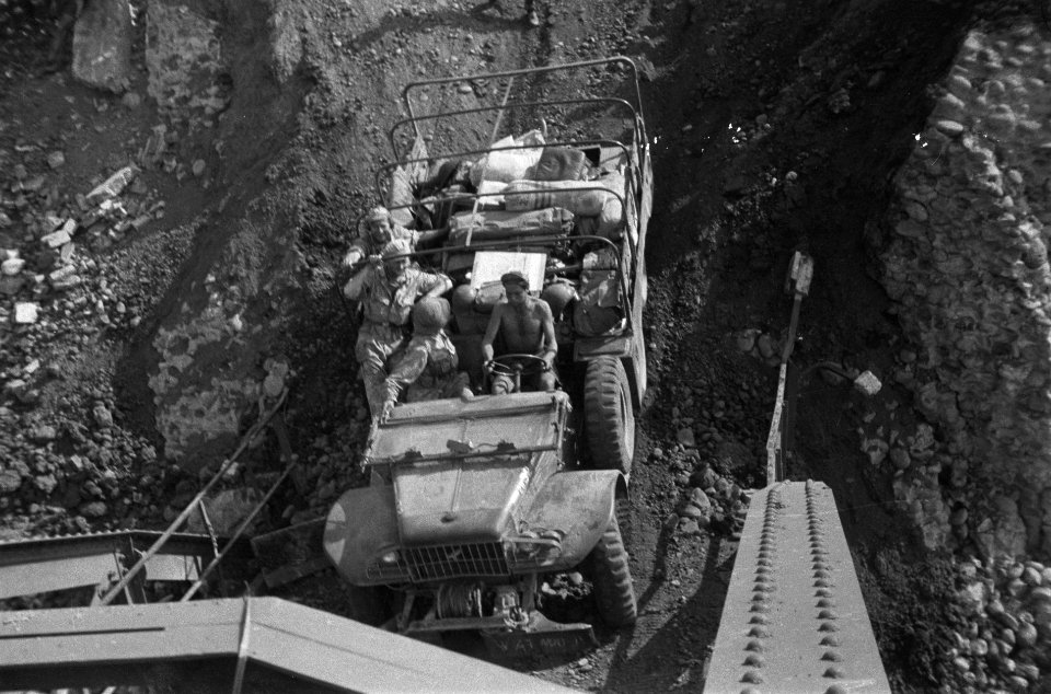 Een vrachtwagen daalt de steile helling af naar de brug over de Tjomal, Bestanddeelnr 1833
