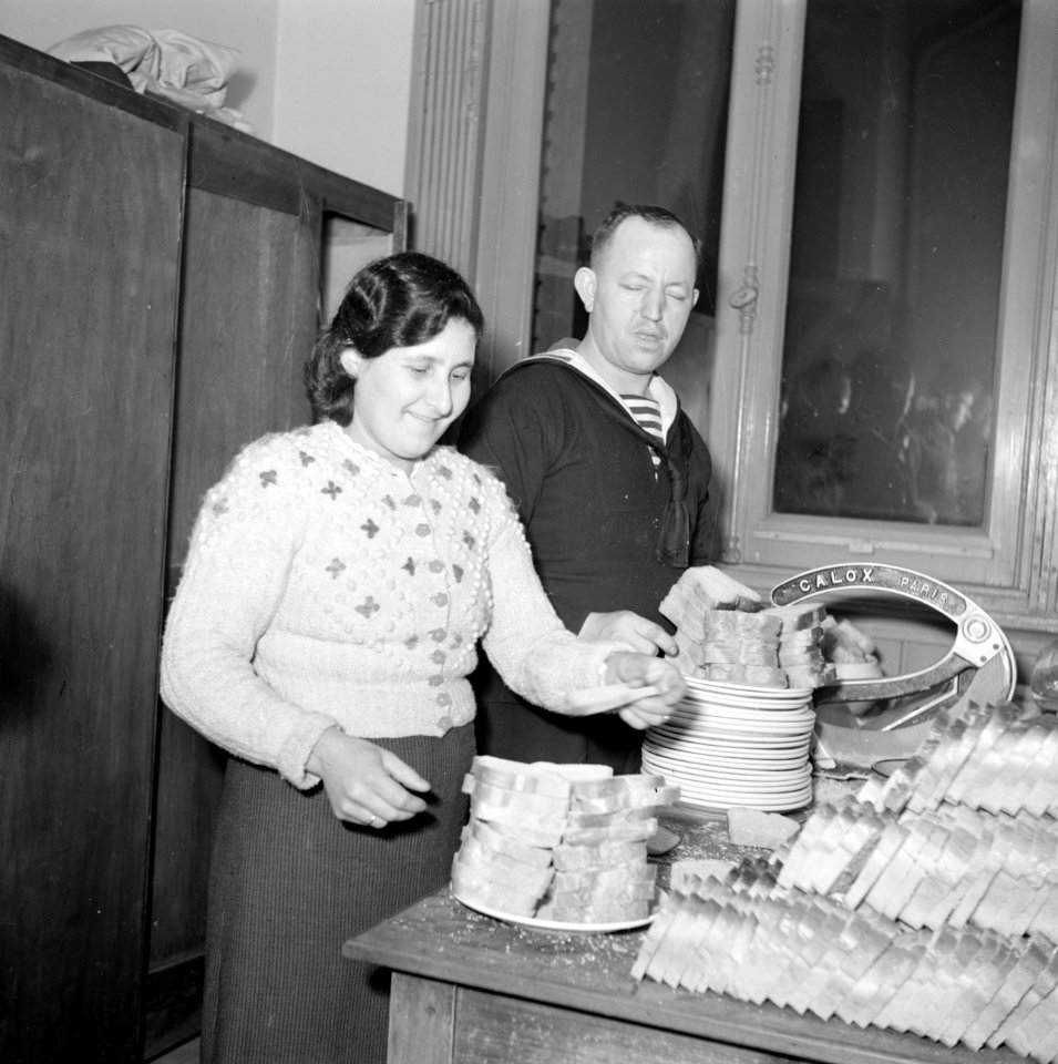 Een vrouw en een matroos bij stapels boterhammen die worden belegd, Bestanddeelnr 255-9478