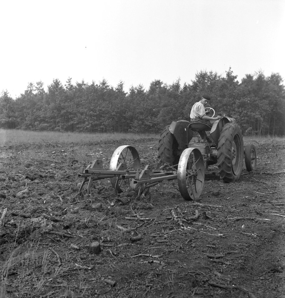 Een vrijgekapt terrein wordt bewerkt met een eg voortgetrokken door een tractor, Bestanddeelnr 251-8243