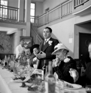 Een man met een corsage houdt een toespraak tijdens een diner, Bestanddeelnr 254-5395