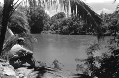 Een man kijkt uit over een rivier in een tropisch landschap, Bestanddeelnr 429-5-1