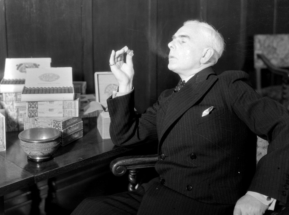 Een man rookt een sigaar in de zaak van Hajenius, Bestanddeelnr 252-1316