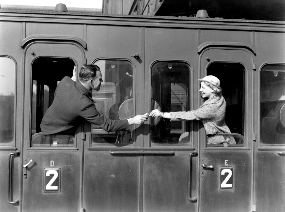 Een man reikt model Eva Waldschmidt een sigaret aan via de deur van een treincou, Bestanddeelnr 189-1267