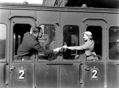 Een man reikt model Eva Waldschmidt een sigaret aan via de deur van een treincou, Bestanddeelnr 189-1267