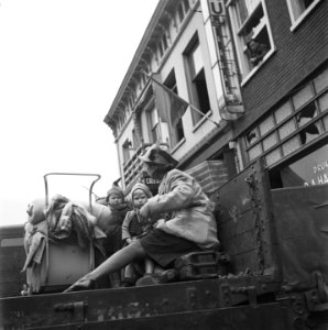 Een vrouw met twee kinderen en een kinderwagen in een laadbak van een millitaire, Bestanddeelnr 900-4249