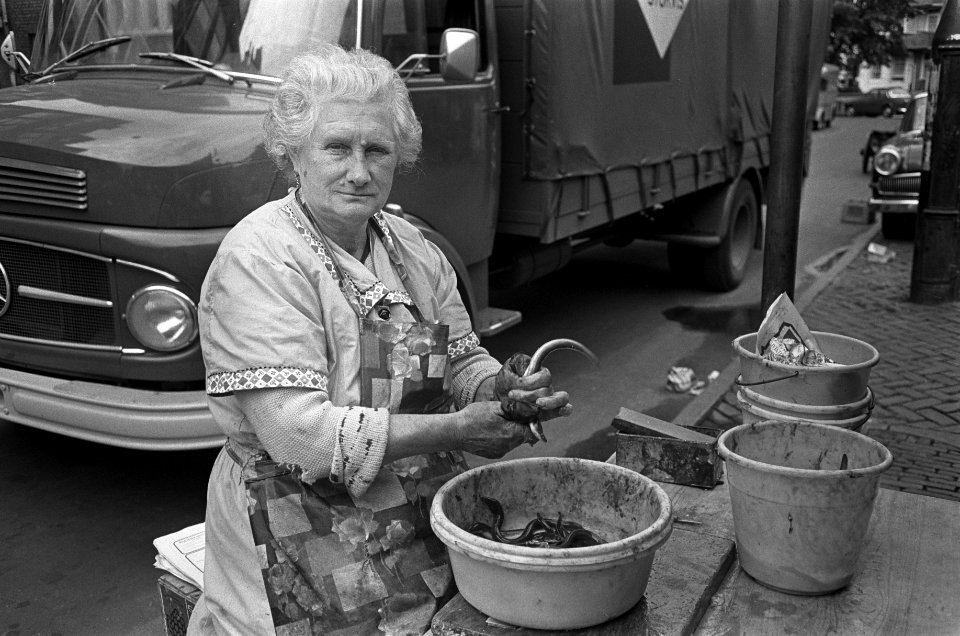 Een vrouw maakt op straat paling schoon, Bestanddeelnr 921-6535