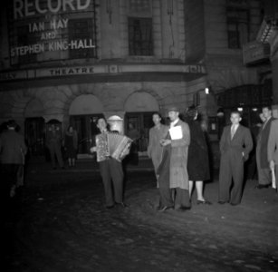 Een accordeonist speelt bij de uitgang van een theater, Bestanddeelnr 191-1021