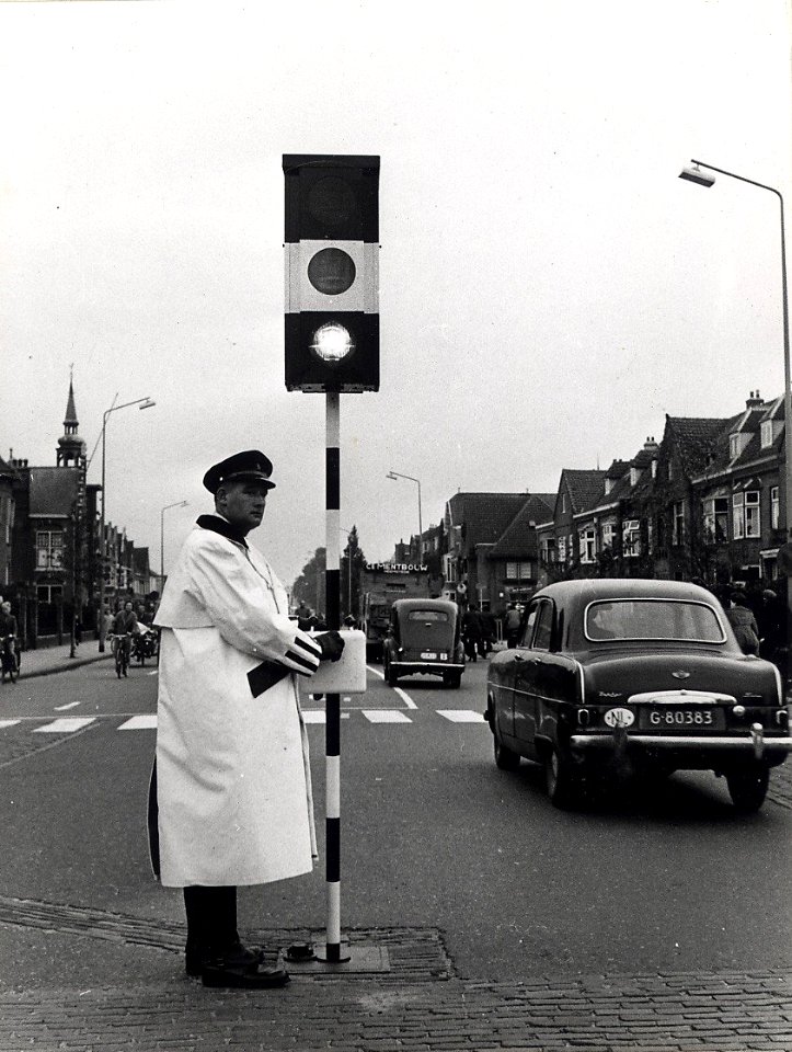 Een agent met een verplaatsbaar verkeersbord regelt het verkeer op de viersprong Zaanenlaan - Rijksstraatweg - Zaanenstraat. Aangekocht in 1977 van fotograaf C.de Boer. Identificatienummer 5, NL-HlmNHA 1478 25900 K 38