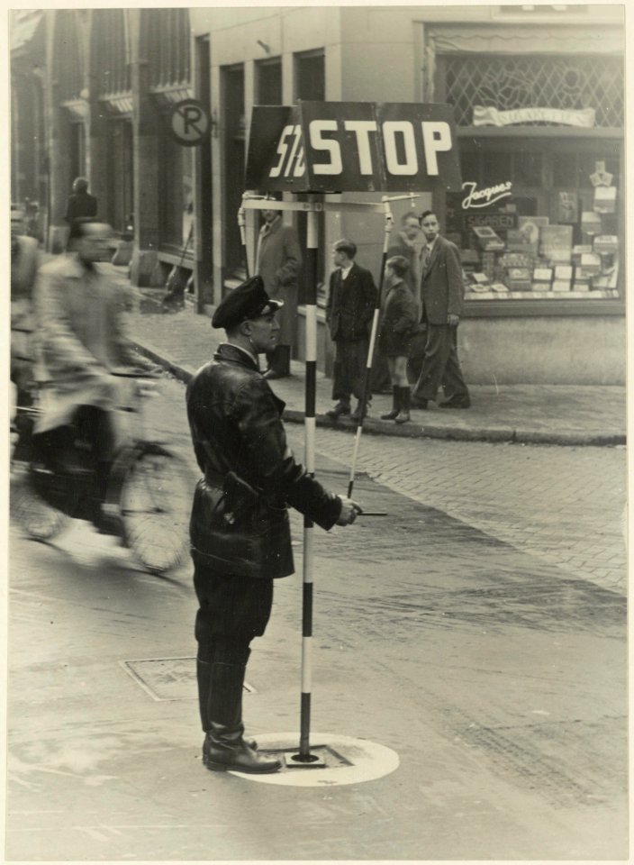 Een agent met een verplaatsbaar verkeersbord regelt het verkeer op de viersprong Zijlstraat-Ged. Oude Gracht-Nassaulaan. Aangekocht in 1977 van fotograaf C. de Boer