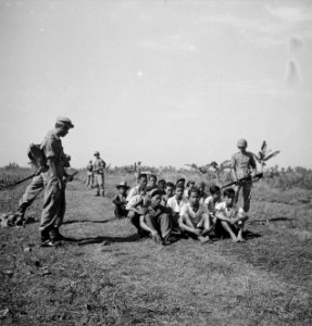 Een groep gevangenen zit op de grond, bewaakt door soldaten voorbeeld van goe…, Bestanddeelnr 15865