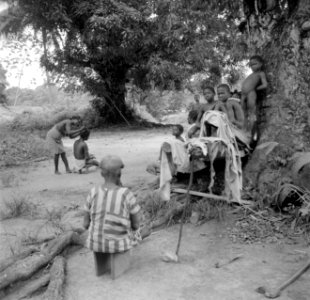 Een groep boslandcreolen in Langetabbetje kijkt toe hoe een boslandcreoolvrouw g, Bestanddeelnr 252-6770