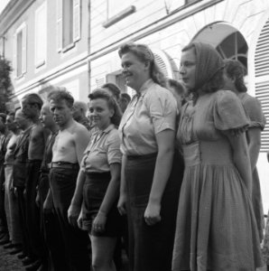 Een groep mannen, en enkele vrouwen, staan aangetreden voor een huis, Bestanddeelnr 900-5909