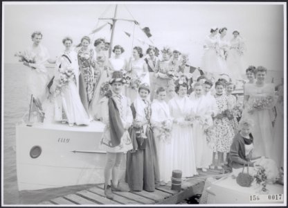 Een groep vrouwen in feestelijke kleding met bloemen en één man en een vrouw in , Bestanddeelnr 156-0017