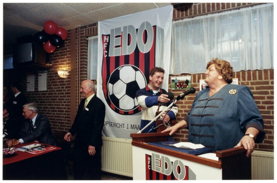 EDO-voorzitter Tom van Wassem glimt terwijl Erica Terpstra uitlegt waarom zijn club de Koninklijke Erepenning krijgt toegekend. NL-HlmNHA 54037362