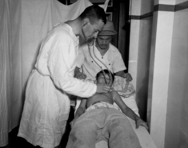 Een dokter luistert met een stethoscoop aan de borstkas van een jongetje, Bestanddeelnr 8503