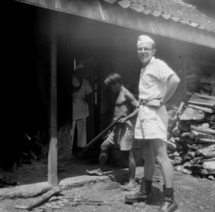 Een Europese man in wit uniform met korte broek en kepi staat bij een soort bara, Bestanddeelnr 14327