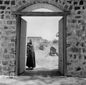 Een franciscaner monnik bij een geopende poort met het gezicht op de deels gerec, Bestanddeelnr 255-1547