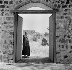 Een franciscaner monnik bij een geopende poort met het gezicht op de deels gerec, Bestanddeelnr 255-1548