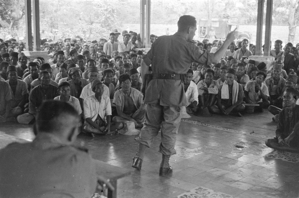 Een officier spreekt een grote groep Indonesiërs op een veranda., Bestanddeelnr 489-6-2