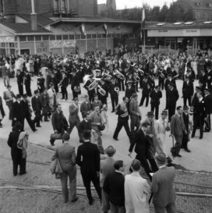 Een blaasorkest staat opgesteld bij het station, Bestanddeelnr 900-7842