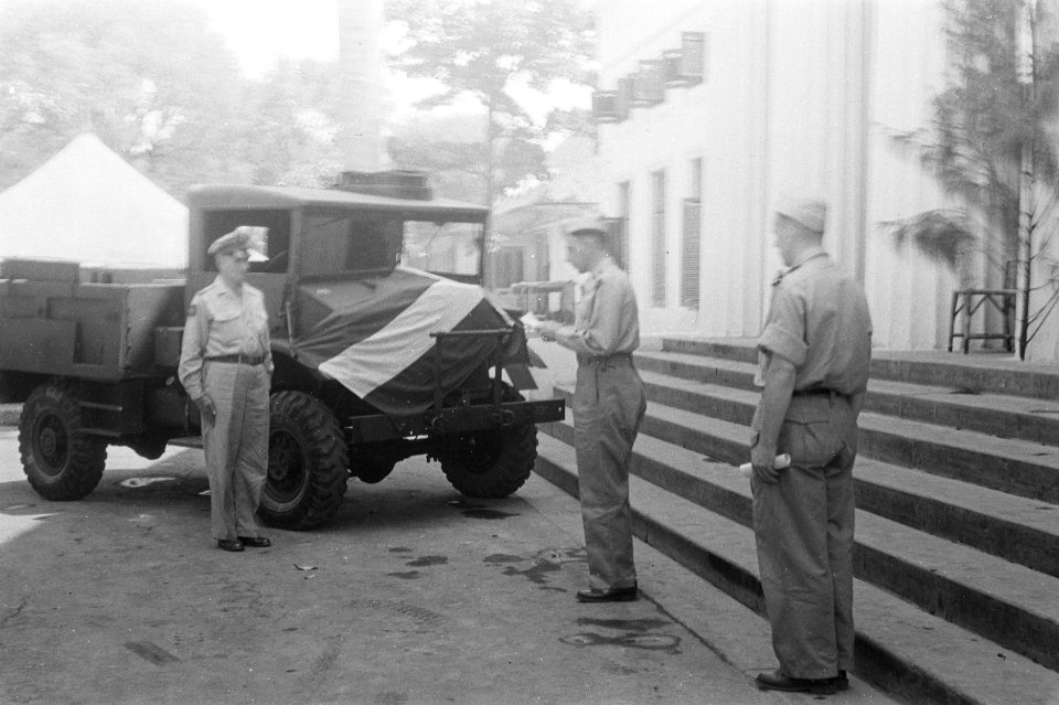 Een officier verlaat een gebouw terwijl hij een document leest Een vrachtwagen, Bestanddeelnr 54-1-6