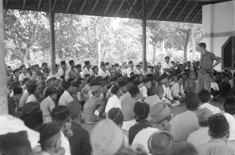 Een officier spreekt een grote groep Indonesiërs op een veranda, Bestanddeelnr 489-5-2