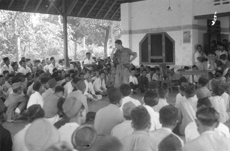Een officier spreekt een grote groep Indonesiërs op een veranda, Bestanddeelnr 489-5-1