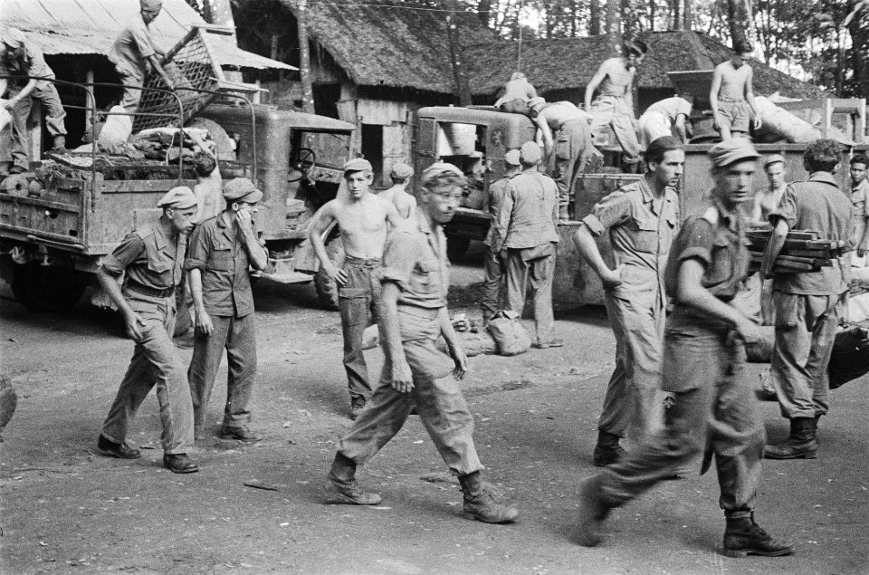 Een convooi miilitaire voertuigen staat stil op een weg langs een kampong. Neder, Bestanddeelnr 503-1-2
