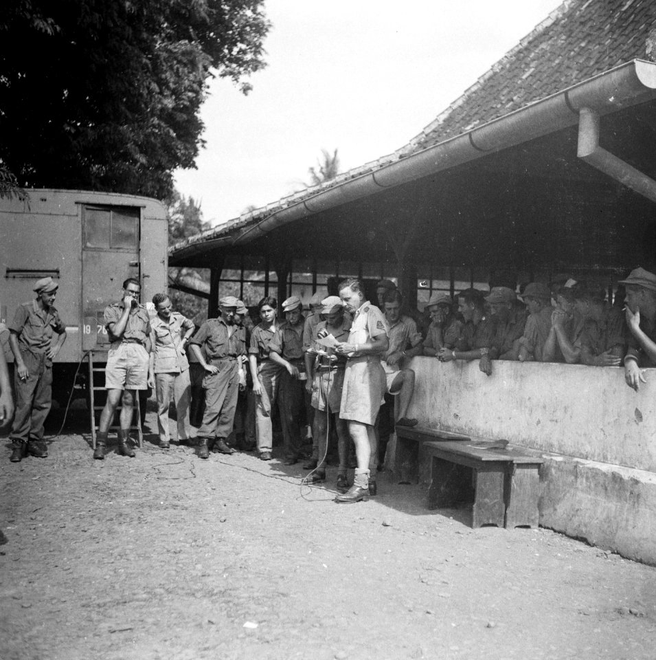 Een Nederlandse officier met een een microfoon omgeven door een grote groep sol, Bestanddeelnr 8111