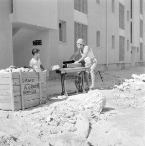 Een nieuwbouwwijk in Dimona. Een man is bezig een trapnaaimachine van het merk A, Bestanddeelnr 255-3569