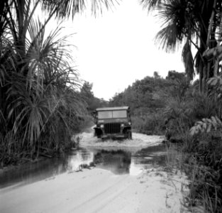 Een jeep op een overstroomde weg bij Zanderij in Suriname, Bestanddeelnr 252-6359