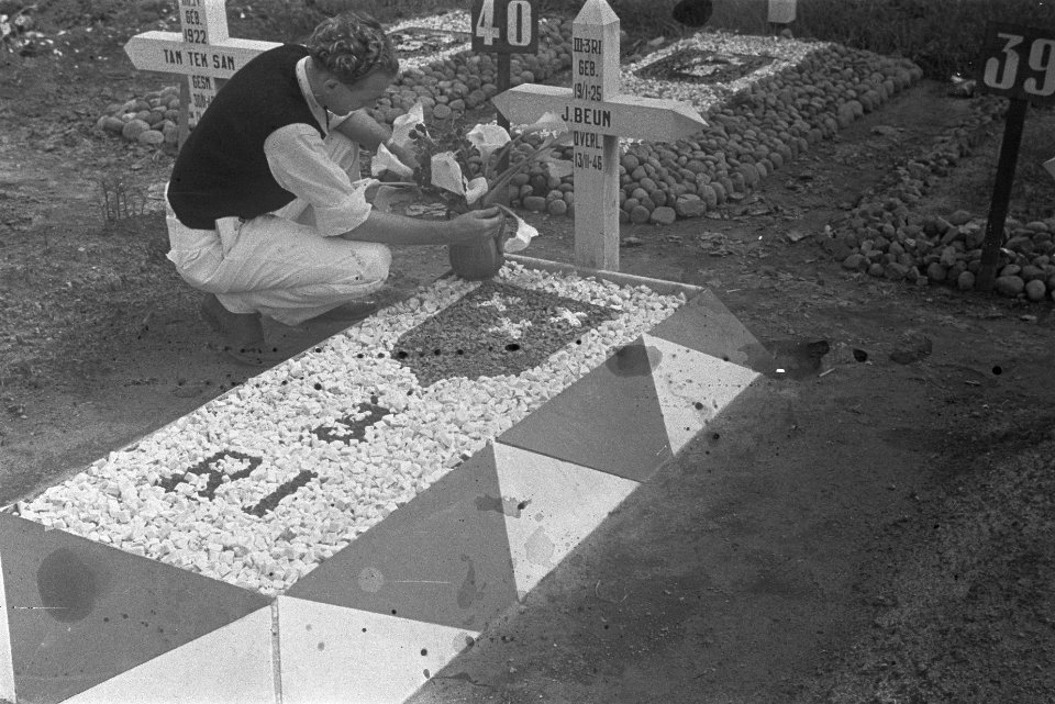 Een jonge man plaatst een vaas met bloemen op het graf van J. Beum van III-3 R.i, Bestanddeelnr 486-3-4
