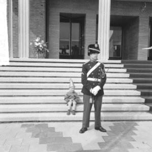 Een jongetje met feestmuts zit op de trappen van het bordes. Voor hem staat een , Bestanddeelnr 917-7978