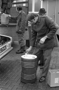 Een jerrycan met benzine wordt op een vrachtwagen geladen op de voorgrond een m, Bestanddeelnr 926-9293