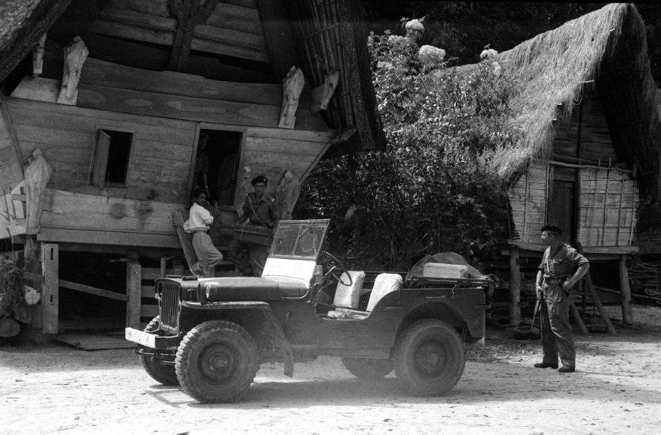 Een jeep staat voor typische Batak-huizen. Een Nederlandse cavalerie-officier dr, Bestanddeelnr 3253