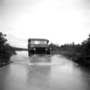 Een jeep op een overstroomde weg bij Zanderij in Suriname, Bestanddeelnr 252-6358