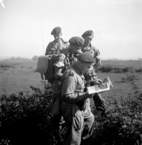 Een kapitein bekijkt een kaart. Bij hem staan drie soldaten, waarvan een met ze, Bestanddeelnr 15707