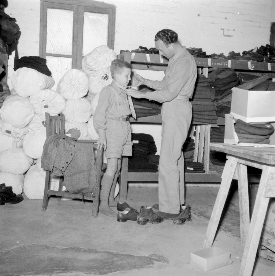 Een gerepatrieerde jongen krijgt kleding uitgereikt in het kledingcentrum in Ata, Bestanddeelnr 255-6851