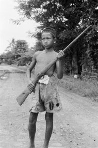 Een jonge Indonesische jongen poseert met een antiek geweer, Bestanddeelnr 466-6-7
