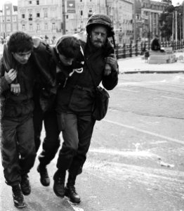 Een gewonde ME-er wordt door twee militairen weggedragen, Bestanddeelnr 930-9730