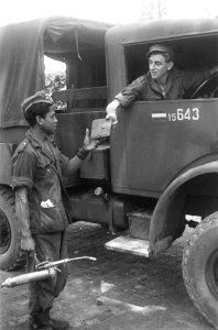 Een chaufferu van een legertruck overhandigt zijn autopapieren aan een man van d, Bestanddeelnr 321