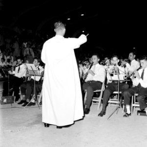Een geestelijke, Frère Pedro, dirigeert een jeugdorkest in het Wilhelminastadion, Bestanddeelnr 252-3864
