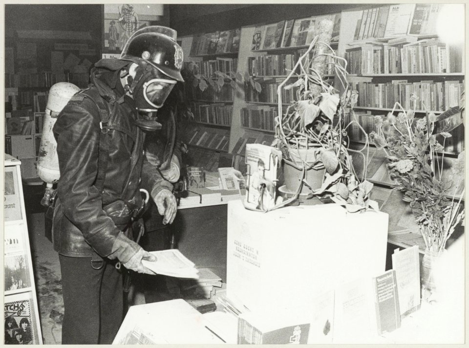 Een brandweerman neemt de schade op van een door een brandbom veroorzaakte brand in boekhandel Agora. NL-HlmNHA 54012597