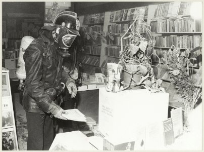 Een brandweerman neemt de schade op van een door een brandbom veroorzaakte brand in boekhandel Agora. NL-HlmNHA 54012597